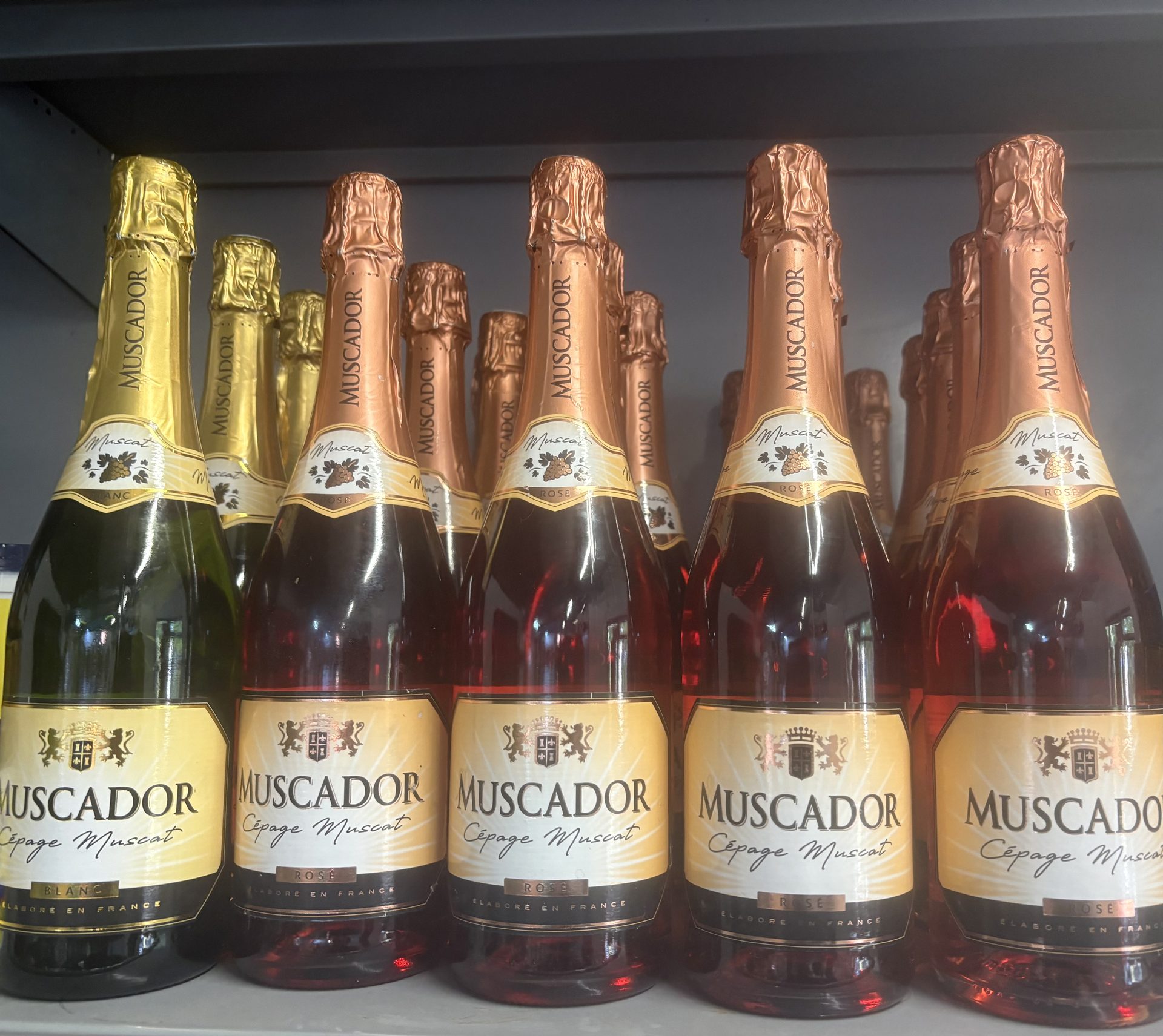 Shelf of Muscador sparkling wine bottles in gold and rosé