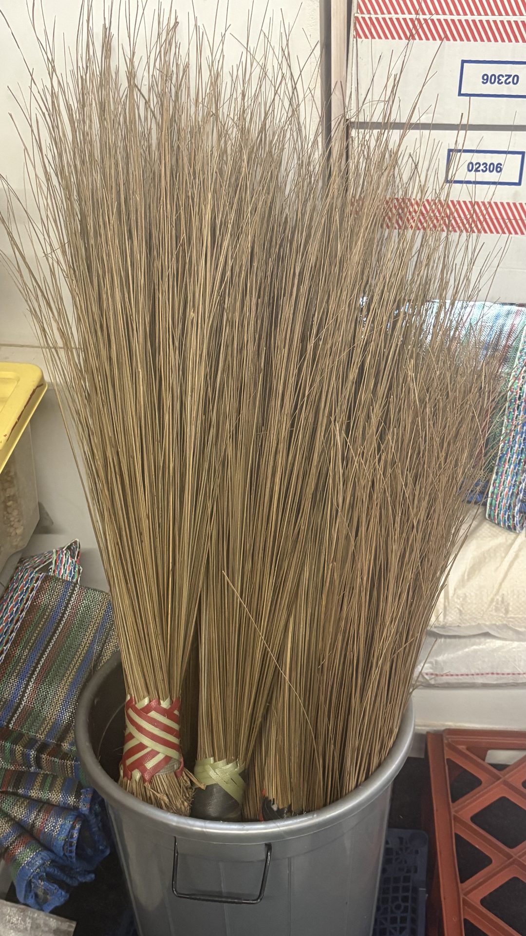 Traditional long-handled brooms standing in a bin in the shop